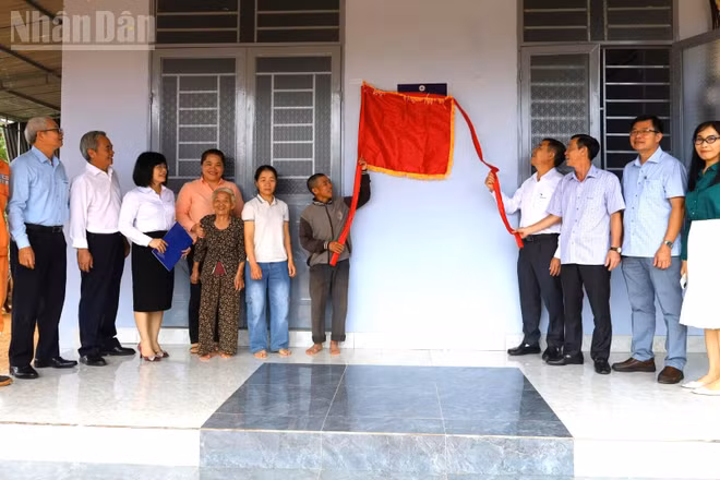 Các đại biểu và gia đình anh Nguyễn Hữu Dũng thực hiện nghi thức kéo băng khánh thành ngôi nhà.