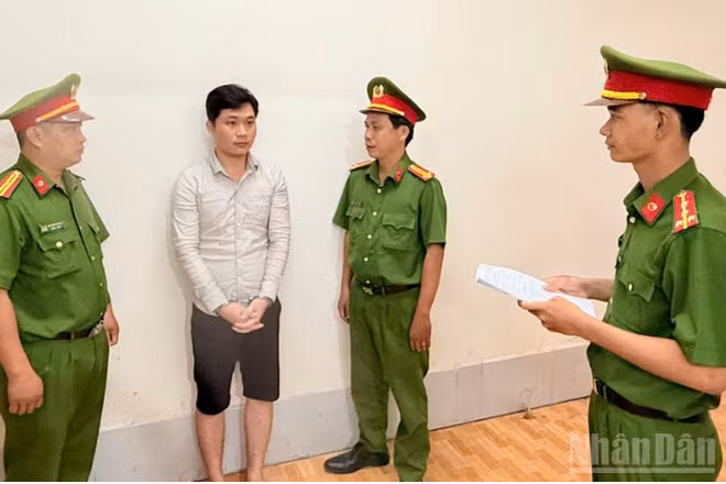 Điều tra viên thi hành lệnh bắt bị can để tạm giam đối với Huỳnh Thanh Huy. (Ảnh: Công an cung cấp)
