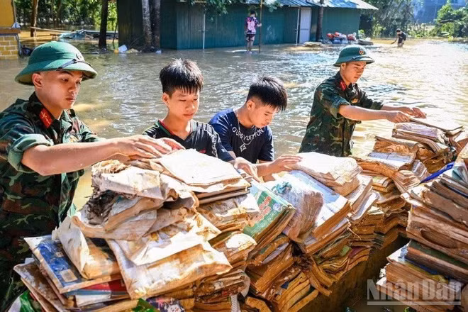 Bộ đội và học sinh đưa sách vở lên phơi trên nơi khô ráo tại Trường phổ thông dân tộc nội trú trung học cơ sở và trung học phổ thông Hữu Lũng, tỉnh Lạng Sơn trong đợt lũ lịch sử 2025 tại địa bàn. (Ảnh: THÀNH ĐẠT)