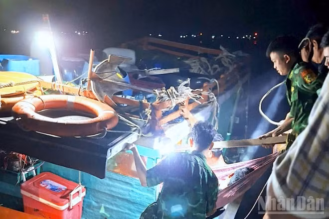 Cán bộ, chiến sĩ Đồn Biên phòng Hòn Chuối hỗ trợ đưa ông Đạt xuống tàu vào bờ tiếp tục cấp cứu, điều trị.