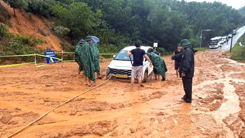 Các lực lượng chức năng tiến hành cứu hộ xe ô-tô bị mặc kẹt tại khu vực bị sạt lở.