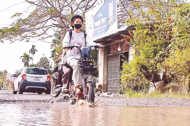 Học sinh đến trường qua đoạn Đường tỉnh 923 hư hỏng, ngập nước tại xã Phong Điền.