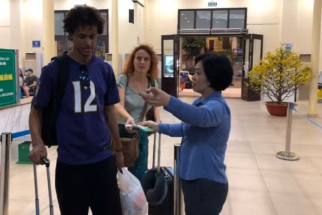 Nhân viên khách vận hướng dẫn hành khách vào ga đi tàu.