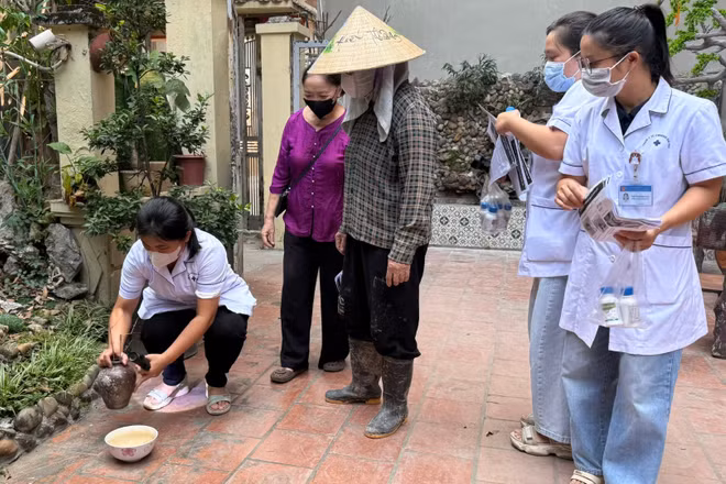 Cán bộ y tế hướng dẫn người dân lược bỏ các vật dụng cụ chứa nước không cần thiết để phòng bệnh sốt xuất huyết. (Ảnh: THẮNG ĐẠT)