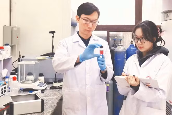 Tiến sĩ Nguyễn Nhật Linh hướng dẫn sinh viên kiểm tra mẫu sản phẩm hạt nano vàng thu được từ quá trình tổng hợp plasma. (Ảnh: MINH ĐỨC)