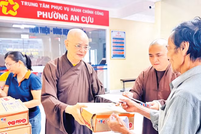 Hòa thượng Thích Huệ Phước (bên trái) trao quà hỗ trợ người dân vùng bị lũ lụt tại phường An Cựu, TP Huế.