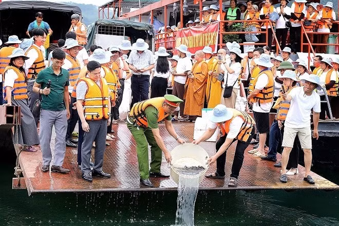 Cán bộ, nhân dân phường Thống Nhất cùng tăng ni, phật tử thả cá giống xuống tại lòng hồ Hòa Bình.