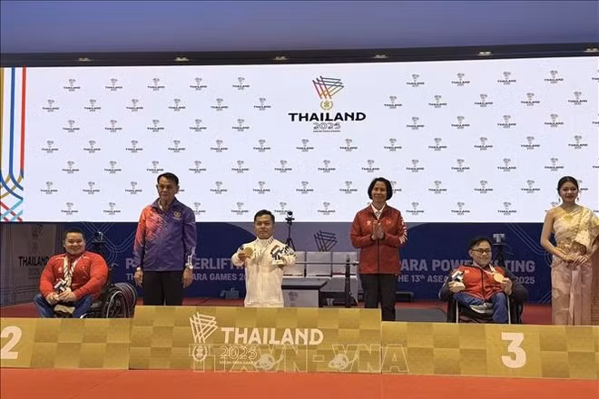 Trưởng đoàn Lê Thị Hoàng Yến chụp ảnh lưu niệm với vận động viên Huy chương Bạc Nguyễn Bình An và Huy chương Đồng Huỳnh Ngọc Phụng. (Ảnh: TTXVN)