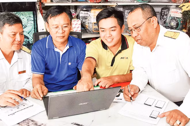 Công chức Thuế cơ sở 4 (An Giang) hướng dẫn chủ hộ kinh doanh cách kê khai hàng hóa. (Ảnh: KIỀU DIỄM)