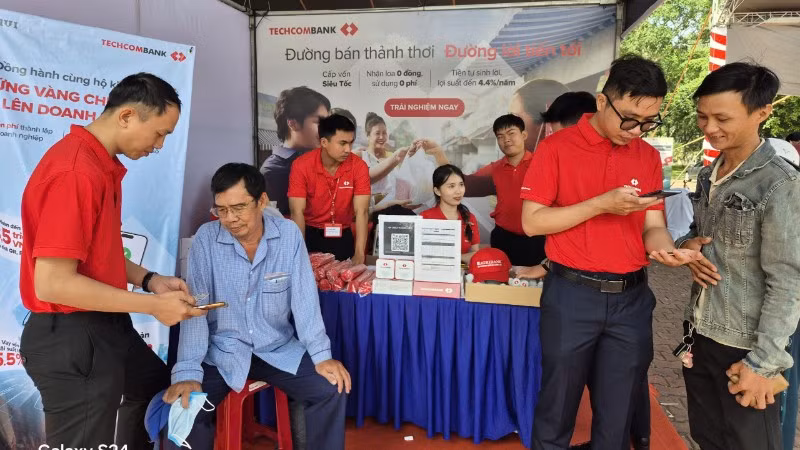 Người dân đến gian hàng của ngân hàng tham gia phiên chợ không dùng tiền mặt mở tài khoản thanh toán.