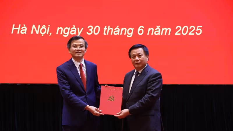 Đồng chí Nguyễn Xuân Thắng, Ủy viên Bộ Chính trị, Giám đốc Học viện Chính trị quốc gia Hồ Chí Minh, Chủ tịch Hội đồng Lý luận Trung ương trao quyết định của Bộ Chính trị về công tác cán bộ cho đồng chí Đoàn Minh Huấn.