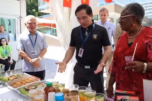 Tham tán Công sứ Phạm Quang Huy (áo đen) giới thiệu gian hàng của Việt Nam với Tổng Giám đốc WTO Ngozi Okonjo-Iweala. (Ảnh: Anh Hiển/TTXVN)