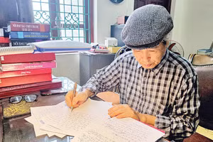 Nhà văn Minh Chuyên miệt mài bên trang bản thảo. (Ảnh: HẢI NAM)