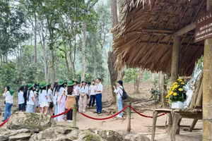 Hướng dẫn viên giới thiệu cho du khách về di tích Lán Nà Nưa, Tuyên Quang. (Ảnh: HUỆ VŨ)