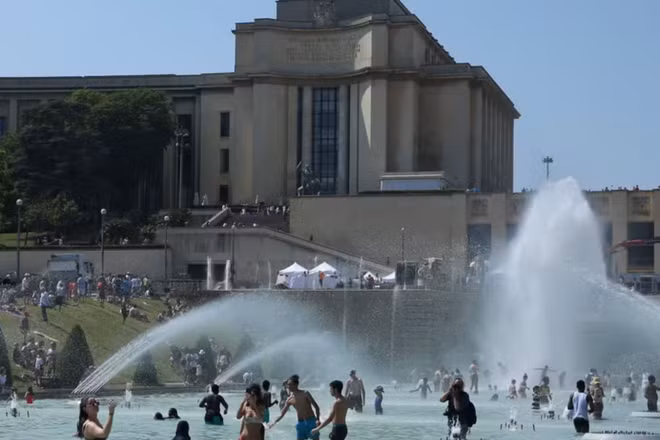 Người dân tránh nóng tại đài phun nước ở Paris, Pháp. (Ảnh: THX/TTXVN)