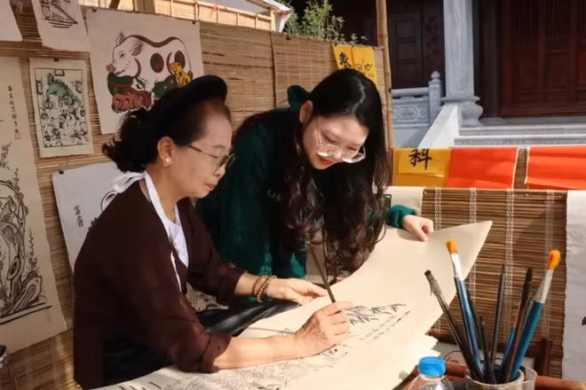 Du khách tìm hiểu quy trình làm tranh dân gian Đông Hồ. (Ảnh: TTXVN)