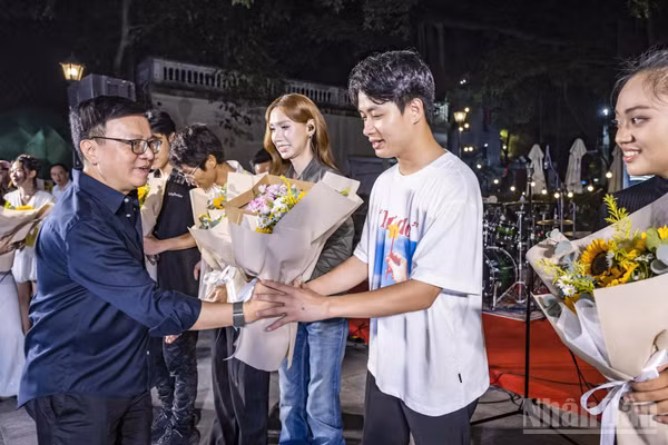 Tổng Biên tập Báo Nhân Dân Lê Quốc Minh tặng hoa cho các ca sĩ biểu diễn tại chương trình. (Ảnh: THÀNH ĐẠT)