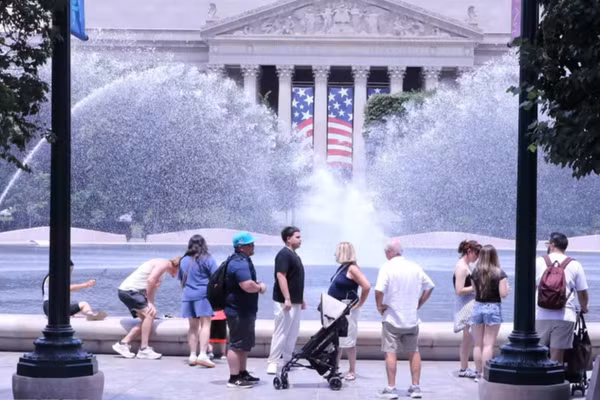 Du khách tránh nắng nóng bên đài phun nước tại khu vực National Mall (Quảng trường Quốc gia) ở thủ đô Washington D.C. (Ảnh: TTXVN)