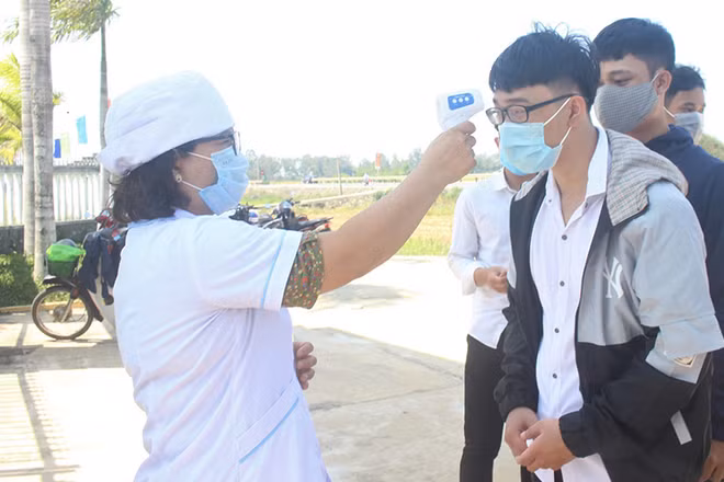 Thí sinh Trường THPT Hùng Vương (huyện Thăng Bình) được kiểm tra nhiệt độ khi đến làm thủ tục dự thi.