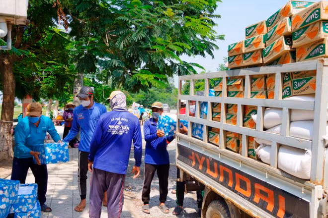 Nhân công đang bốc gạo sang xe của Tổng Hội Việt kiều Campuchia. (Ảnh: Phú Quý)