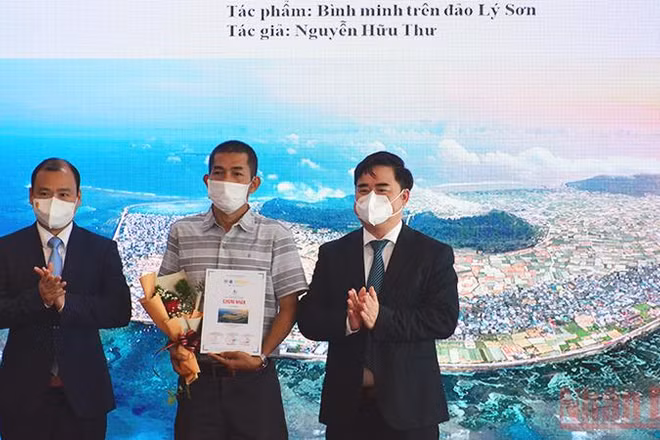 Ông Lê Hải Bình (bên trái) và PGS, TS Phạm Minh Tuấn trao giải nhất cho tác phẩm "Bình minh trên đảo Lý Sơn" của tác giả Nguyễn Hữu Thư.