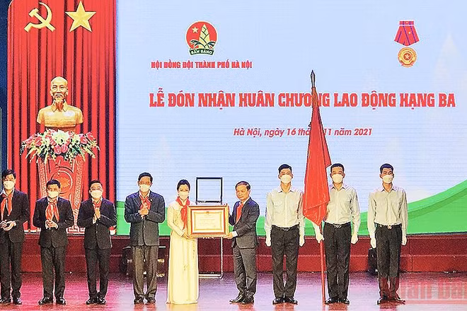 Đồng chí Phạm Tất Thắng (thứ tư từ bên phải sang trong ảnh) thừa ủy quyền của Chủ tịch nước, trao Huân chương Lao động hạng ba tặng Hội đồng Đội thành phố Hà Nội. 