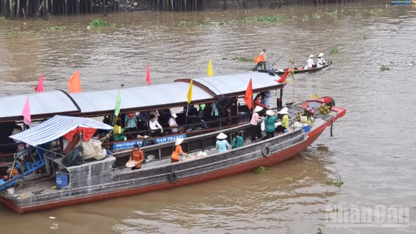 Tái hiện cảnh mua bán giữa thương lái và khách du lịch tại chợ nổi Cái Bè sáng 4/12/2025.