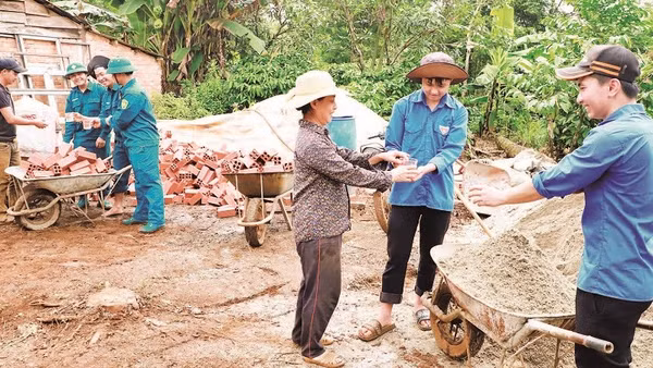 Anh Hoàng Văn Mạnh cùng mẹ là bà Hoàng Thị Đoàn mời nước, động viên lực lượng hỗ trợ xây dựng nhà mới cho gia đình.