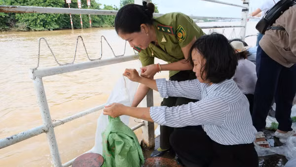 Các đại biểu tham dự buổi lễ tiến hành thả con giống tái tạo nguồn lợi thủy sản xuống sông Đồng Nai. (Ảnh: CTV)
