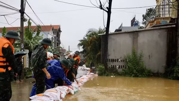 Lực lượng bộ đội hỗ trợ đắp đê bao ngăn nước khu dân cư ven sông Bùi. (Ảnh: TTXVN)
