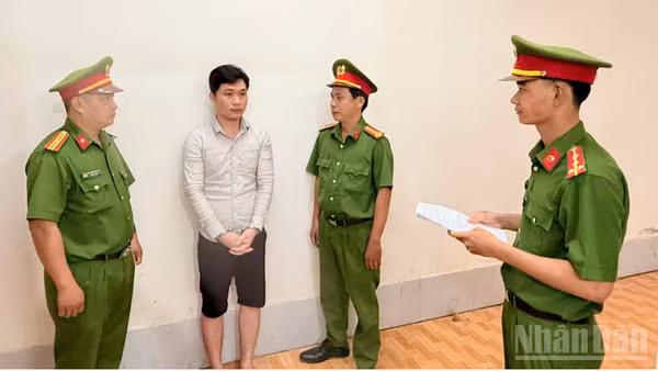 Điều tra viên thi hành lệnh bắt bị can để tạm giam đối với Huỳnh Thanh Huy. (Ảnh: Công an cung cấp)