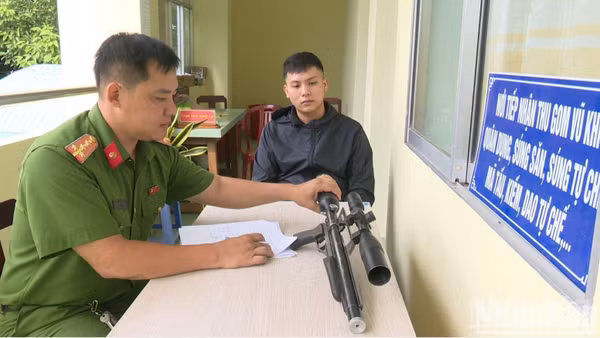 Anh Phạm Minh Sang giao nộp khẩu súng quân dụng nhặt được cho Công an xã Chợ Gạo. (Ảnh: LÊ HOÀI)