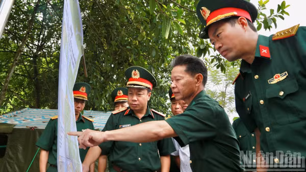 Thiếu tướng Nguyễn Ngọc Ngân và đoàn công tác cùng các nhân chứng lịch sử kiểm tra vị trí hài cốt liệt sĩ trên bản đồ. (Ảnh: THANH SƠN)