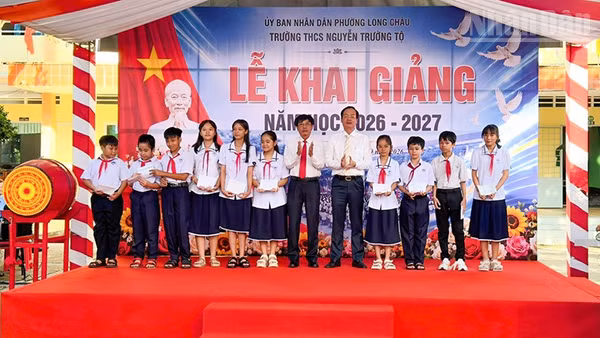 Chủ tịch Ủy ban nhân dân tỉnh Vĩnh Long Trần Trí Quang trao học bổng cho học sinh Trường trung học cơ sở Nguyễn Trường Tộ. (Ảnh: BÁ DŨNG)