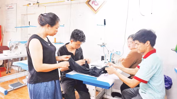 Chị Đinh Thị Quỳnh Nga (ngoài cùng, bên trái) hướng dẫn các bạn trẻ thực hành kỹ thuật cắt may. Ảnh: VĂN HỌC