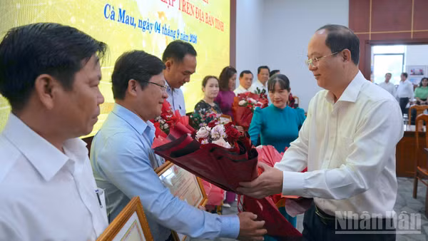 Đồng chí Nguyễn Hồ Hải, Ủy viên Trung ương Đảng, Bí thư Tỉnh ủy Cà Mau (bên phải) tặng hoa và Bằng khen của Chủ tịch tỉnh cho các tập thể, cá nhân có thành tích xuất sắc trong sắp xếp trường, lớp. (Ảnh: HỮU TÙNG)