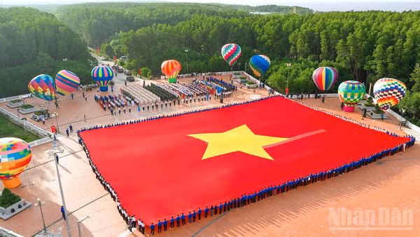 Toàn cảnh lá cờ Tổ quốc trải rộng tại sân Cột cờ Hà Nội ở Đất Mũi, chung quanh là các khinh khí cầu rực rỡ sắc màu. (Ảnh: HỮU TÙNG)