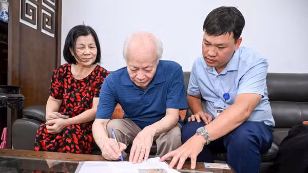 Anh Lê Minh Thiện (phải) hỗ trợ ông Nguyễn Xuân Bình làm thủ tục ủy quyền lương hưu. Ảnh: Thành Đạt 