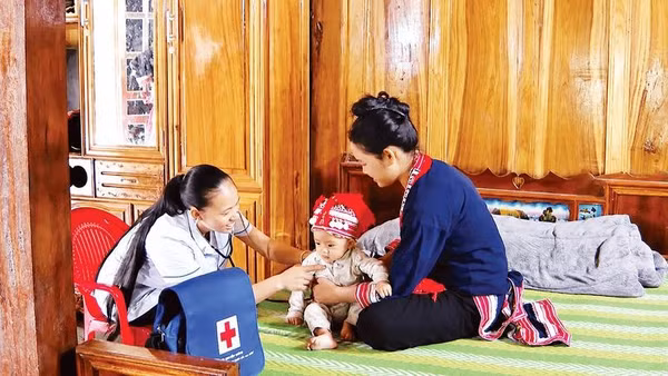 Chị Triệu Thị Ké, y tế thôn Sơn Thành, xã Hồ Thầu đến tận nhà kiểm tra sức khỏe cho trẻ.