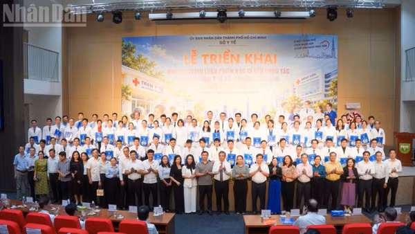 Lãnh đạo Thành phố Hồ Chí Minh và các đại biểu chụp ảnh cùng 79 bác sĩ luân phiên về trạm y tế. (Ảnh: KHANG ANH)
