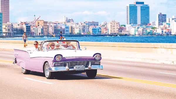 Du khách đi xe cổ ngắm thủ đô La Habana. (Ảnh: KIMKIM.COM)
