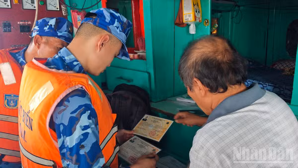 Tổ tuần tra, kiểm soát tiến hành kiểm tra giấy tờ tàu cá ngư dân đang hành nghề trên biển. (Ảnh: VĂN THƯỜNG)