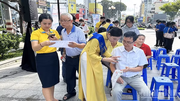Thanh niên tình nguyện và học sinh hỗ trợ người dân phường Chợ Quán tiếp cận và sử dụng các ứng dụng, tiện ích số thiết yếu. (Ảnh: HOÀNG LIÊM)