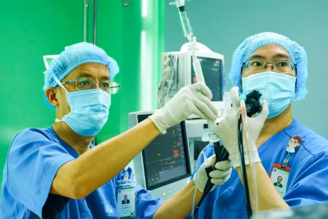 Phó Giáo sư, Tiến sĩ Lê Thượng Vũ (bên trái) thực hiện thủ thuật nội soi phế quản siêu âm sinh thiết.