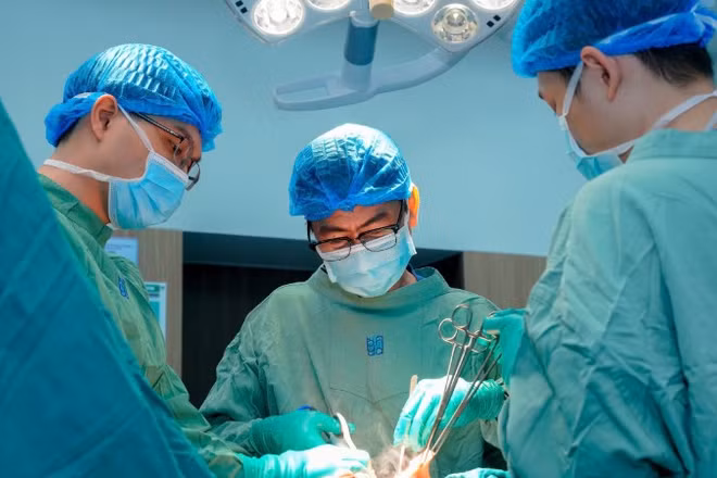 Bác sĩ chuyên khoa II Nguyễn Triệu Vũ, Trưởng khoa Tuyến vú, Bệnh viện Đại học Y Dược Thành phố Hồ Chí Minh và ê-kíp phẫu thuật cho bệnh nhân. 