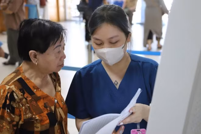 Nhân viên công tác xã hội hướng dẫn bệnh nhân làm thủ tục khám bệnh.