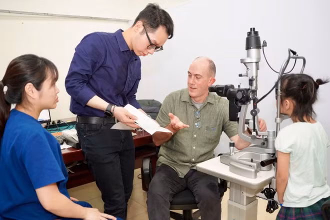 Tiến sĩ Timothy Robert Fricke,Giám đốc Nghiên cứu và Giáo dục tại Viện Nghiên cứu Thị giác Quốc gia, Trường Cao đẳng Khúc xạ Nhãn khoa Úc, đồng thời là Giáo sư danh dự Đại học Y Hà Nội khám cho em nhỏ.