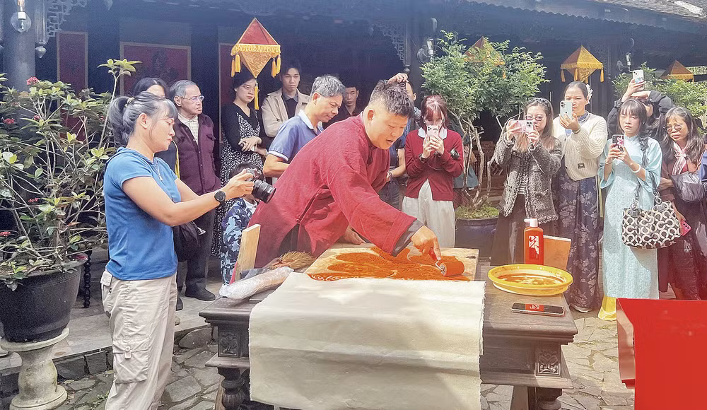 Nghệ nhân Nguyễn Công Đạt thực hiện in liễn làng Chuồn trong không gian Ngự Hà Viên, Huế. (Ảnh: MẠNH HÀO)