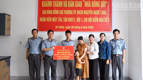 Đồng chí Vũ Thành Long, cán bộ Chi đội Kiểm ngư số 3 (thứ hai từ trái sang) trao kinh phí hỗ trợ nhà đồng đội cho gia đình đồng chí Nguyễn Ngọc Long. (Ảnh: NGUYỄN DŨNG)