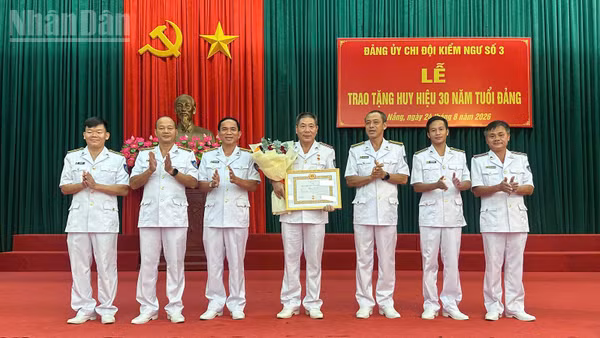 Chụp ảnh lưu niệm với đảng viên được nhận Huy hiệu 30 năm tuổi Đảng. (Ảnh: NGUYỄN DŨNG)